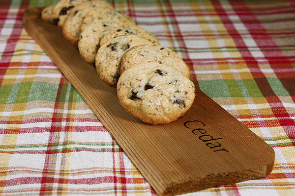 Grace's Sweet Life Italian Chocolate Chip Cookies A photo of hazelnut cookies with chocolate chunks arranged in a row on a rectangular-shaped cedar board.