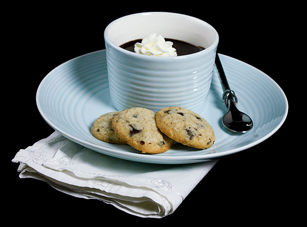 pots de creme pots A photo of a chocolate pots de creme garnished with a dollop of sweetened cream served on a blue dessert dish with chocolate hazelnut cookies.