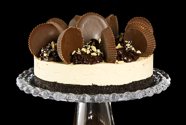 Grace's Sweet Life Oreo Cake A close up photo of an Oreo Cake decorated with Reese's Peanut Butter Cups.