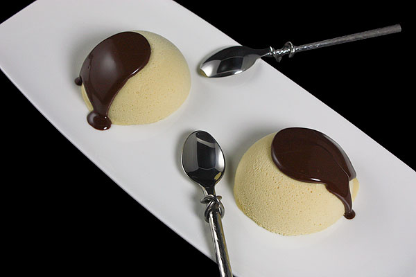 Grace's Sweet Life-What is Semifreddo? A photo taken looking down on two Salted Caramel Semifreddo desserts with hot chocolate sauce on a white rectangular dessert dish with dessert spoons.
