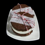 Grace's Sweet Life Gelato Ice Cream A photo of three Chocolate Sablée-Gelato Ice Cream Sandwiches wrapped in a strip of parchment paper with red and white string displayed on a white rectangular-shaped dessert dish.