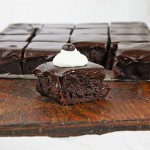 Espresso Chocolate Brownies from Grace's Sweet Life A photo of a slab of Espresso Chocolate Brownies with one removed, decorated with whipped cream and a chocolate covered espresso bean, and placed in front.