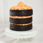 Chocolate Cake with Pumpkin from Grace's Sweet Life A close up photo of a Chocolate Cake with Pumpkin decorated with orange-tinted Vanilla Bean-Swiss Meringue Buttercream displayed on a white cake stand.