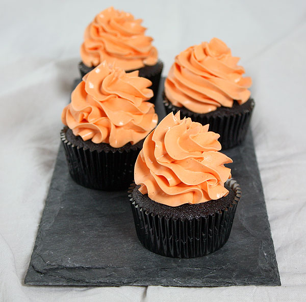 Chocolate Cupcakes with Pumpkin from Grace's Sweet Life A photo taken looking down on four Chocolate Cupcakes with Pumpkin decorated with orange-tinted Vanilla Bean frosting.