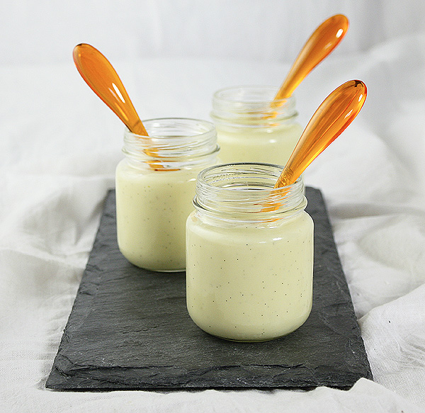 Vanilla Pudding from Grace's Sweet Life Homemade Vanilla Pudding in glass jars displayed on rectangular-shaped slate board with orange acrylic dessert spoons.
