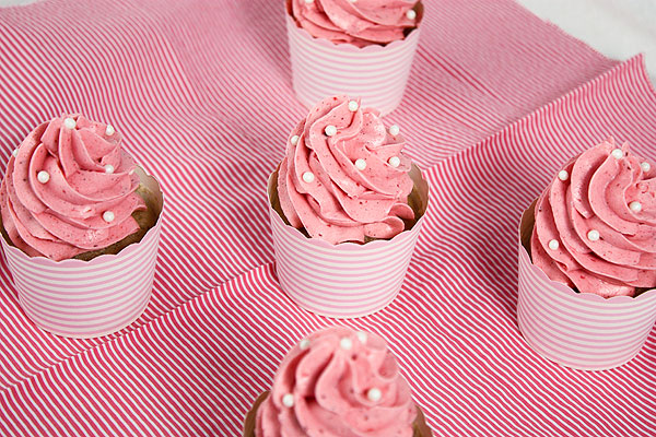 A photo taken looking down on five Strawberry Cupcakes with Pink Strawberry Frosting decorated with white sugar pearls.