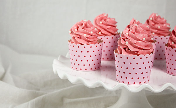 A close up and cropped photo of Strawberry Cupcakes displayed on white cake stand.