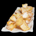 A photo of Chiacchiere on a white rectangle shaped serving dish.