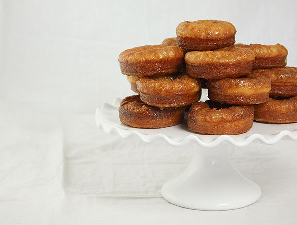Cropped photo of Croissant Doughnuts stacked high on white cake stand.