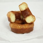 Photo of two Croissant Doughnuts, one cut in half exposing the many interior layers.