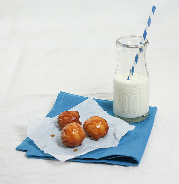 Photo of Frittelle di Ricotta, Sweet Italian Fritters with Jug of milk displayed on blue napkin with white and blue striped straw.