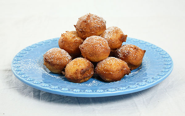 Photo of Italian Sweet Fritters dusted with confectioners' sugar piled up on a blue dessert dish.