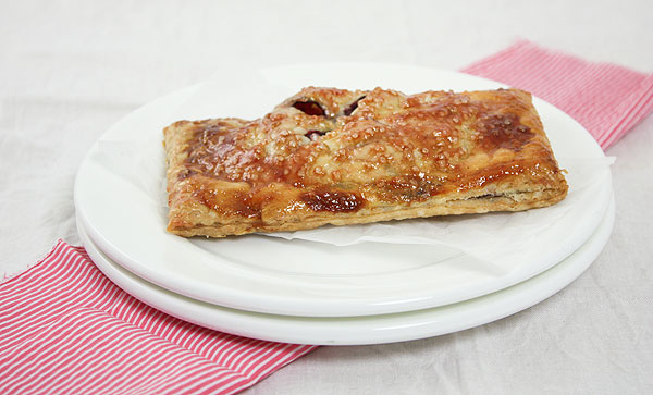 Close up photo of a Blackberry Hand Pie on white dessert dish lined with baking paper.