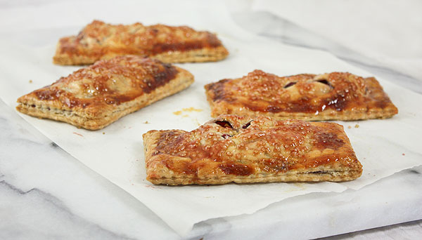 Close up photo of blackberry hand pies displayed on marble pastry board.
