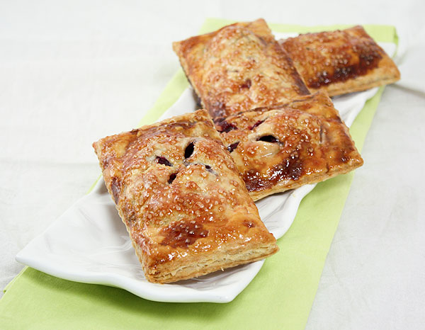 Blackberry Hand Pies displayed in a row on rectangle-shaped, white textured serving dish.