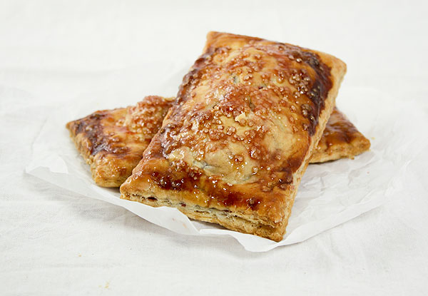 Close up photo of individual Blackberry Pies displayed on baking paper.