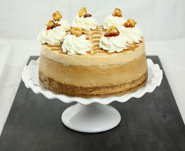 Photo of Dulce de Leche Cheesecake with Caramel Mousse displayed on white cake stand.